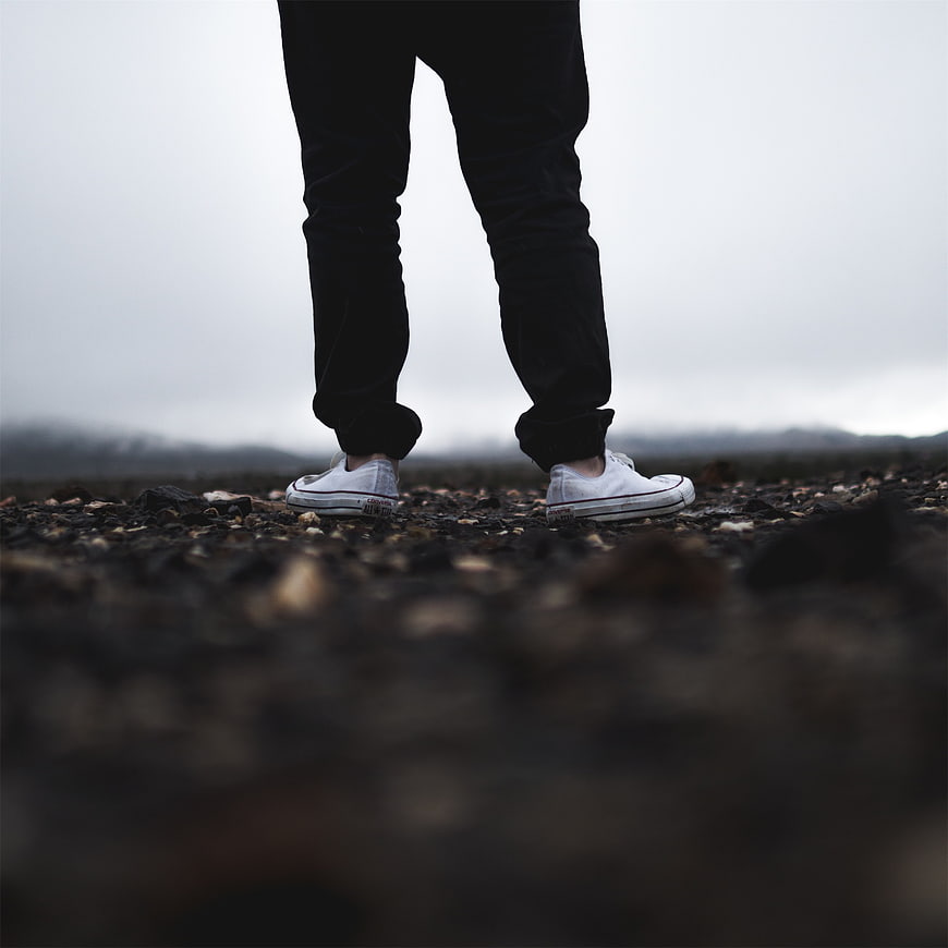 Low angle shot of white sneakers on rocky ground