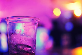 Condensation on plastic cup with ice and colorful bokeh background