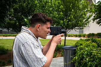 Young Man Filming with Vintage Video Camera in Park