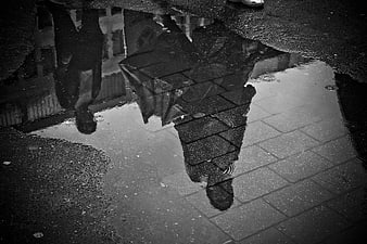 Black and white reflection of person in rain puddle