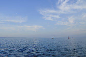 Sailboats on Calm Blue Sea with Moon in Sky