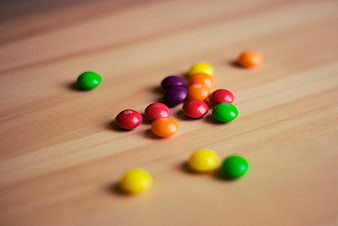 Colorful Skittles candies scattered on a wooden table