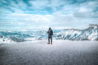 Man standing on snowy mountain peak overlooking alps