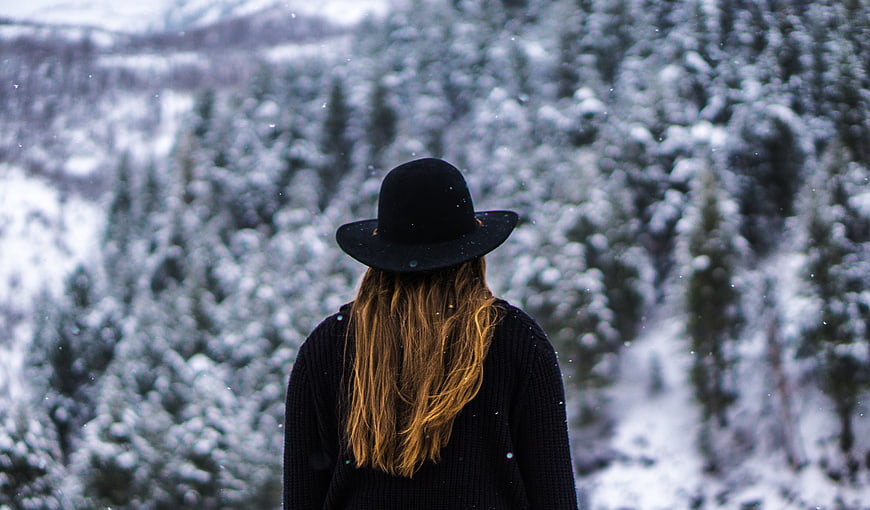 Woman in Black Hat Looking at Snowy Forest