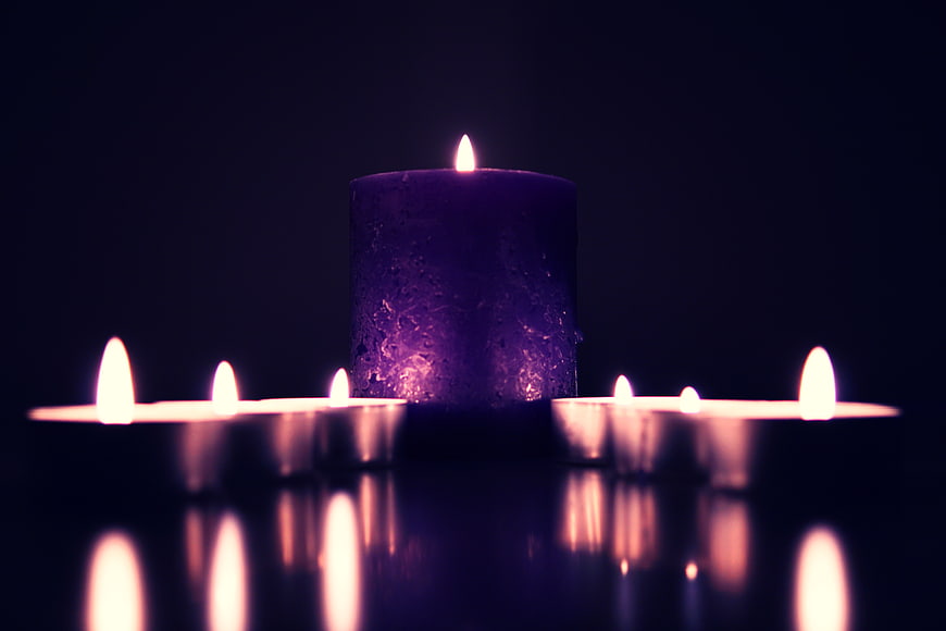 Purple Candle with Tea Lights on Reflective Surface