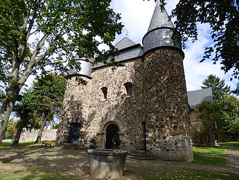 Historic stone church with conical towers and stone fountain
