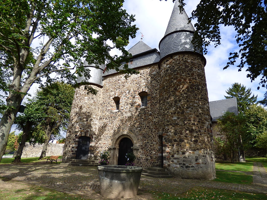Historic stone church with conical towers and stone fountain