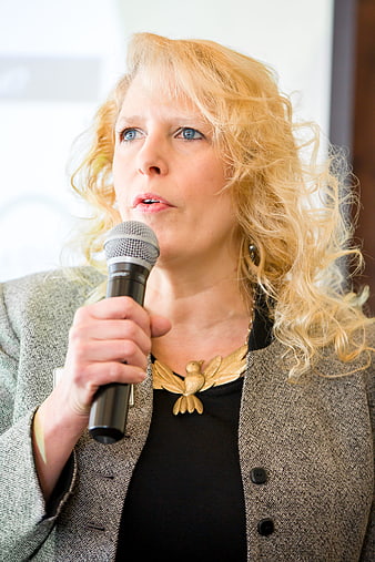 Professional blonde woman speaking into microphone at conference