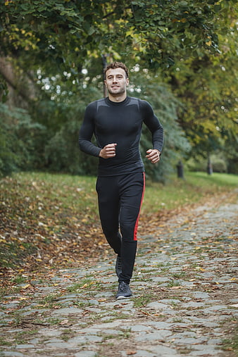 Fit Man Running on Cobblestone Path in Autumn Park