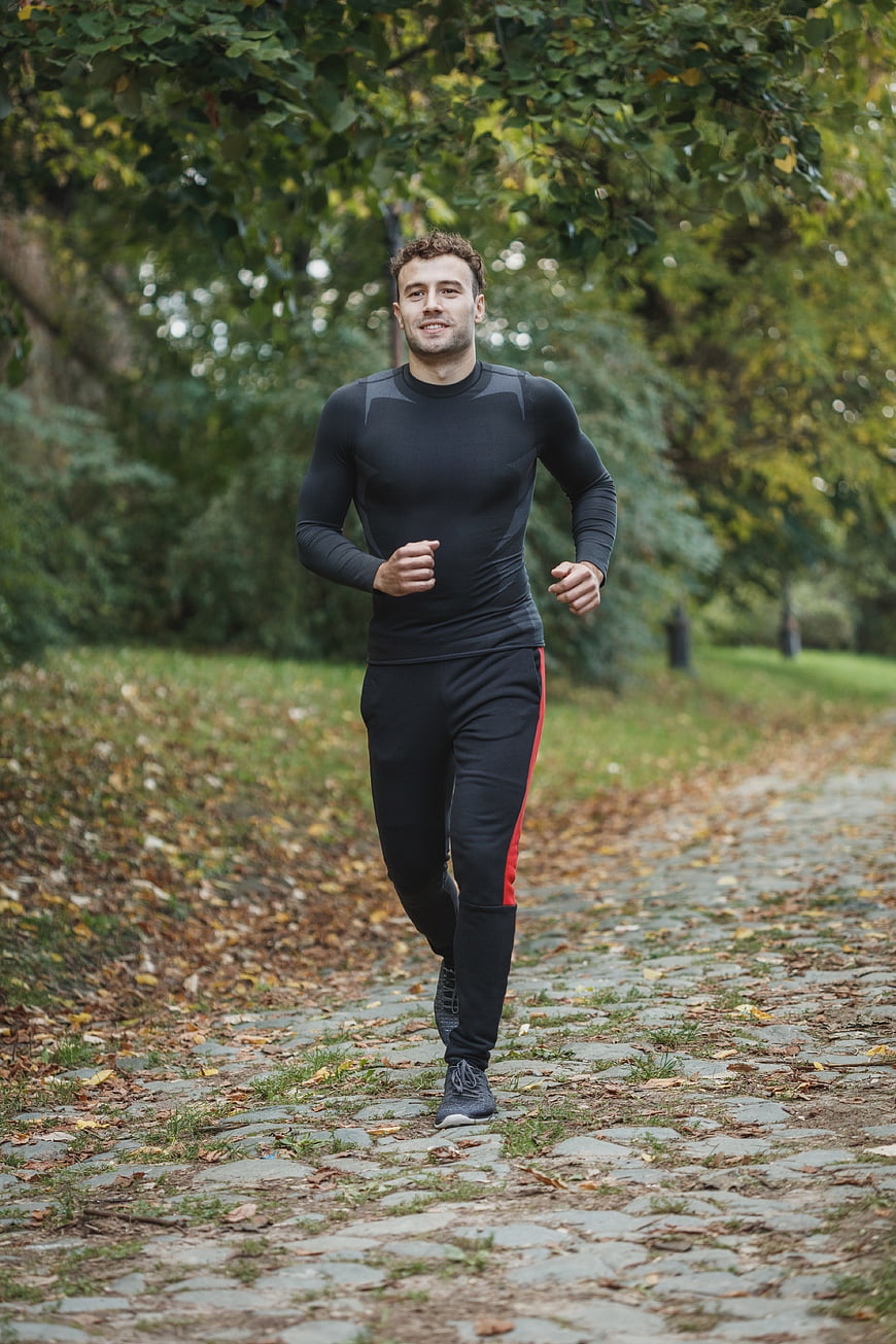 Fit Man Running on Cobblestone Path in Autumn Park