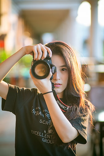 Young woman photographer holding DSLR camera outdoors