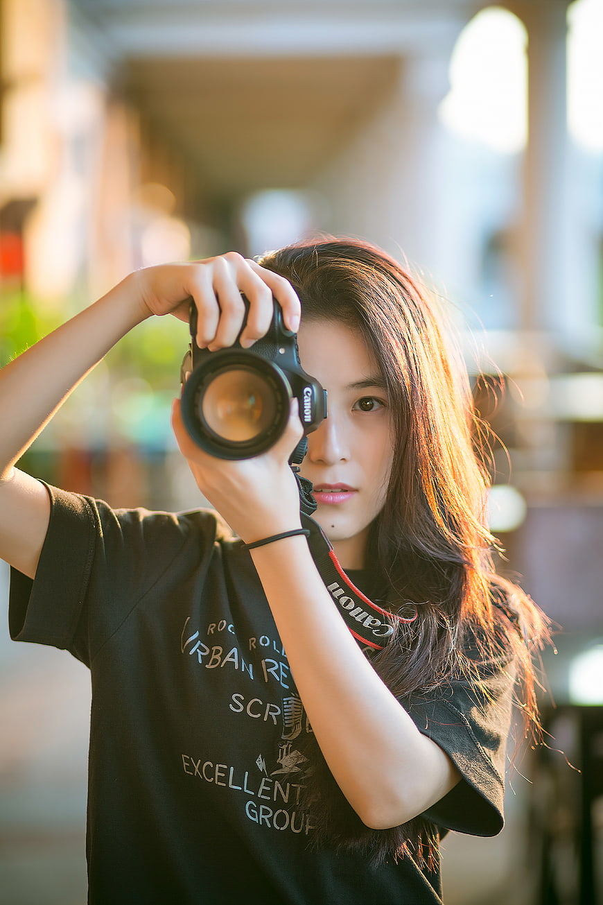 Young woman photographer holding DSLR camera outdoors