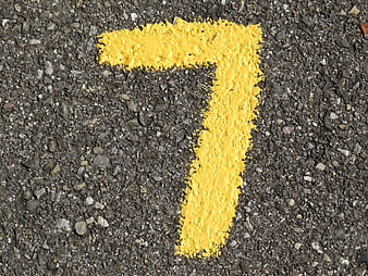 Yellow Number Seven Painted On Rough Asphalt Road Surface