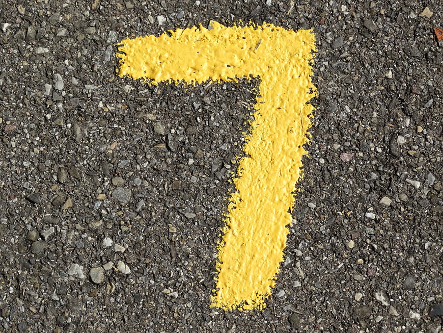 Yellow Number Seven Painted On Rough Asphalt Road Surface