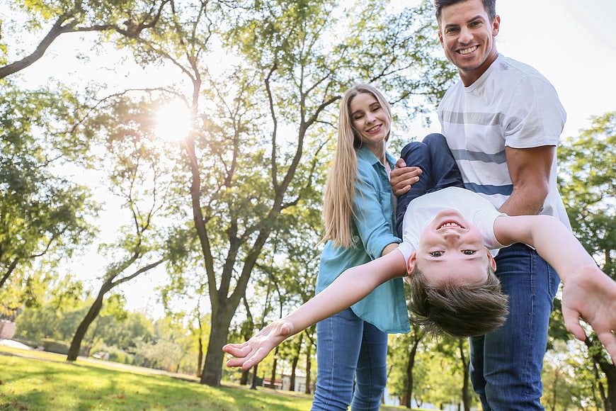 Happy family playing with son in sunny park