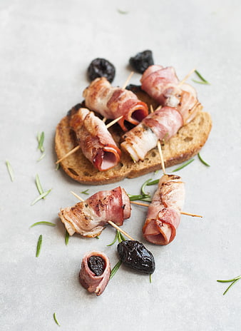 Bacon-wrapped dates on toast with rosemary garnish