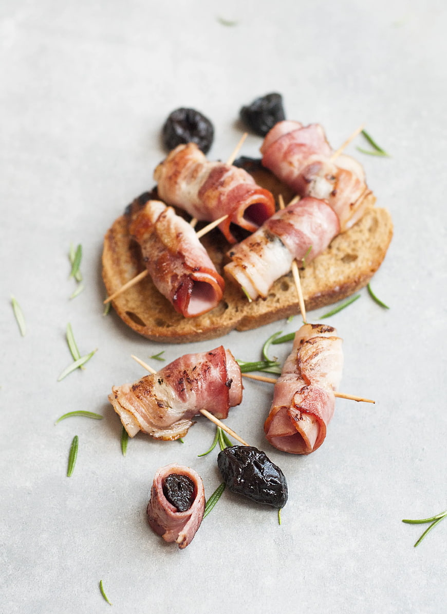 Bacon-wrapped dates on toast with rosemary garnish
