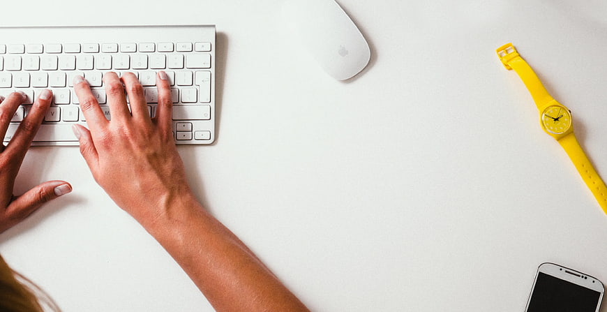 Top View of Hands Typing on White Keyboard with Yellow Watch