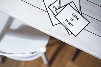 Minimalist cards with Less is More quote on white table