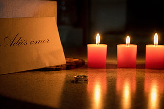 Wedding Ring and Note Reading Adios Amor Beside Three Lit Candles