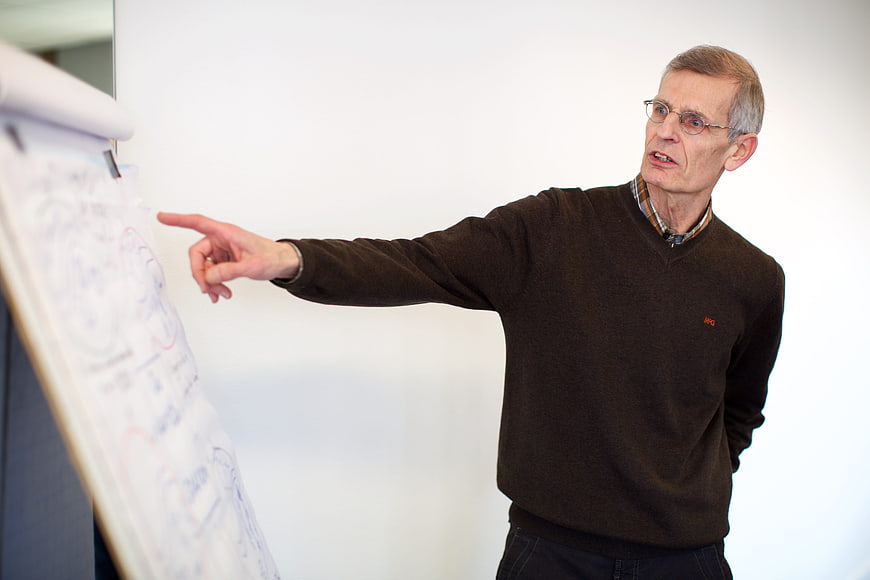 Senior man presenting business strategy on whiteboard