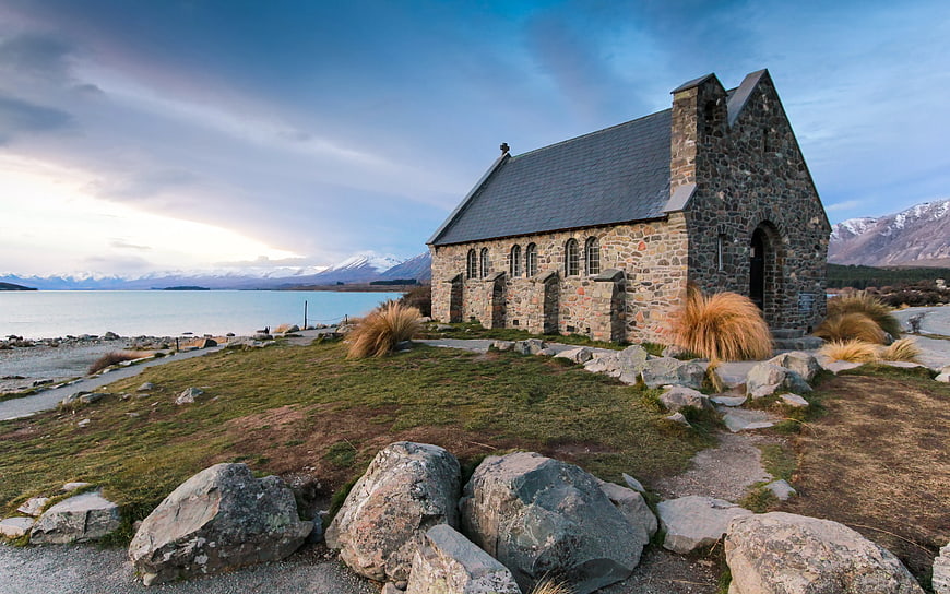 Stone Church by Lake with Snowy Mountains Background