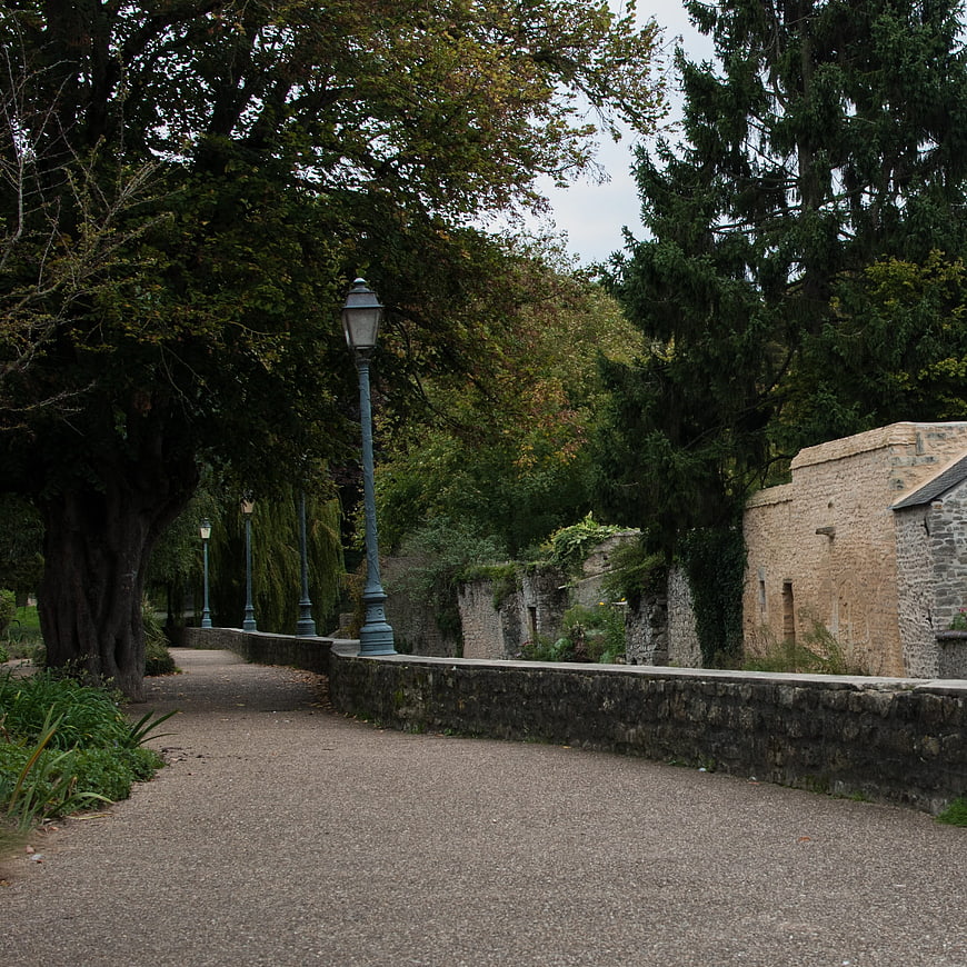 Quiet gravel path in park with stone walls and trees