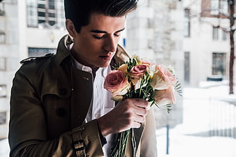Young man smelling bouquet of pink roses in winter