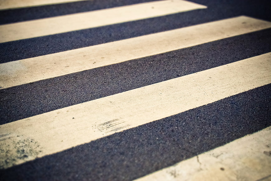Close-up of a zebra crossing on an asphalt road with diagonal white stripes
