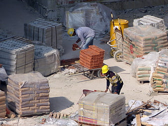 Construction workers moving bricks and materials at a building site