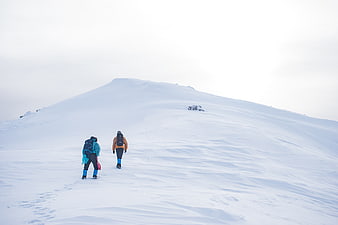Two hikers climbing a snowy mountain peak in winter