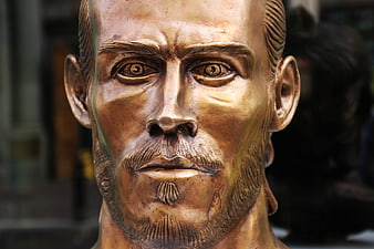 Close-up of a bronze footballer statue head with detailed facial features