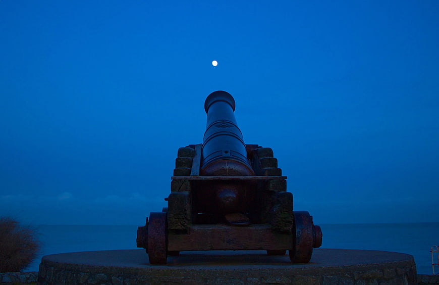 Silhouette of Old Cannon Pointing at Moon Over Ocean