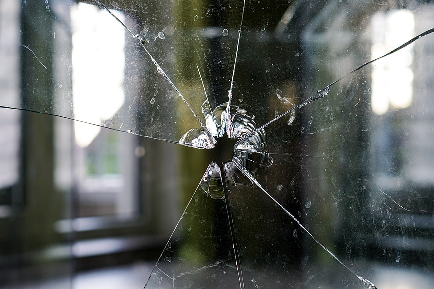 Broken Glass Pane With Central Impact Hole And Radiating Cracks