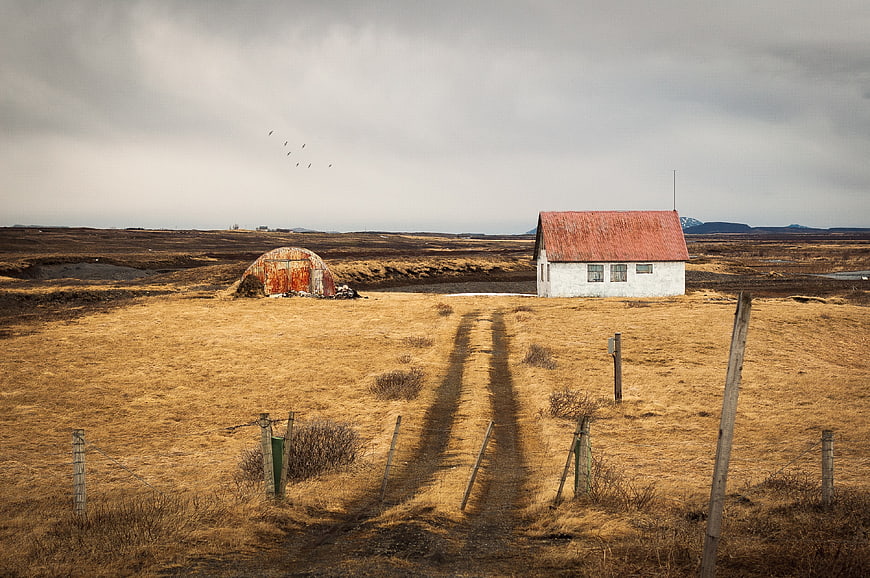 Rustic white house with red roof in barren landscape