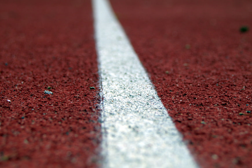 Close-up of white line on red running track surface