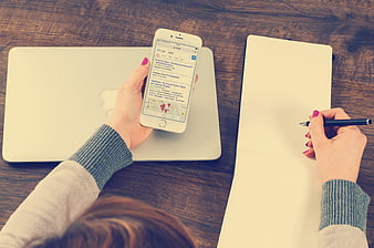 Woman planning travel on smartphone and notebook at desk
