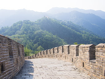 Great Wall of China stone pathway leading through lush green mountains