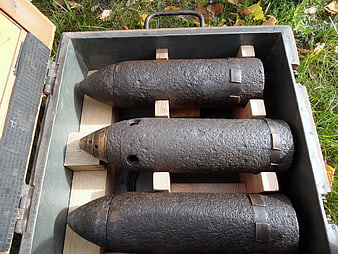 Three rusty antique artillery shells in a metal transport crate