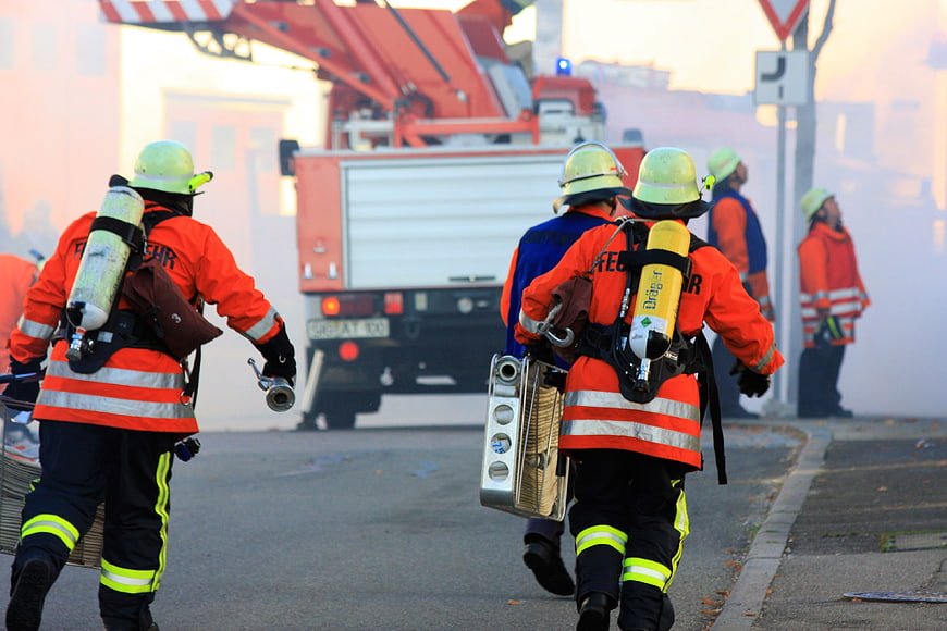 Volunteer Firefighters Carrying Equipment Toward Fire Truck