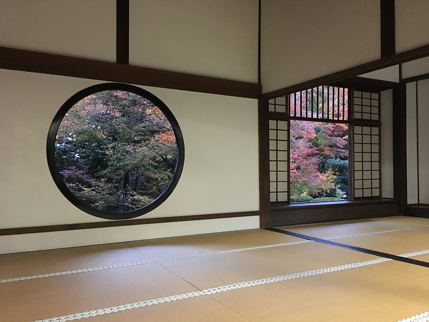 Traditional Japanese Tatami Room With Circular Window And Autumn Garden View
