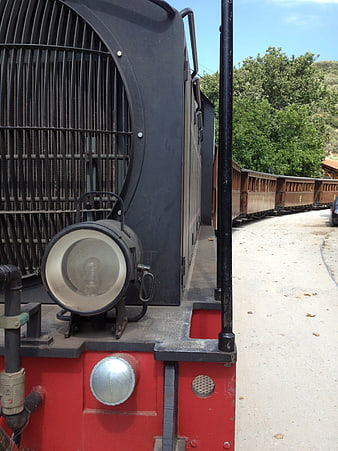 Close-up of vintage red and black train engine with wooden carriages