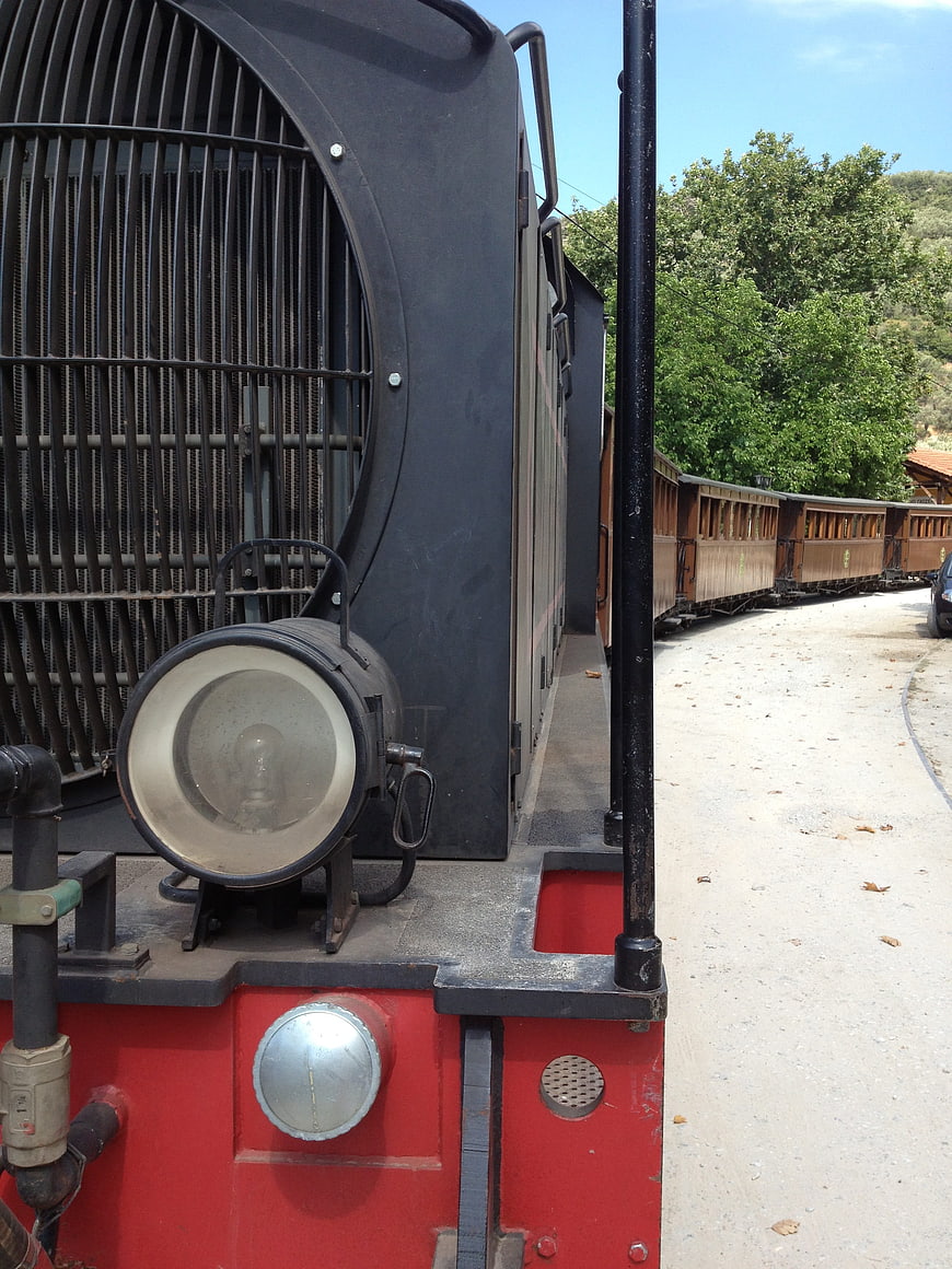 Close-up of vintage red and black train engine with wooden carriages