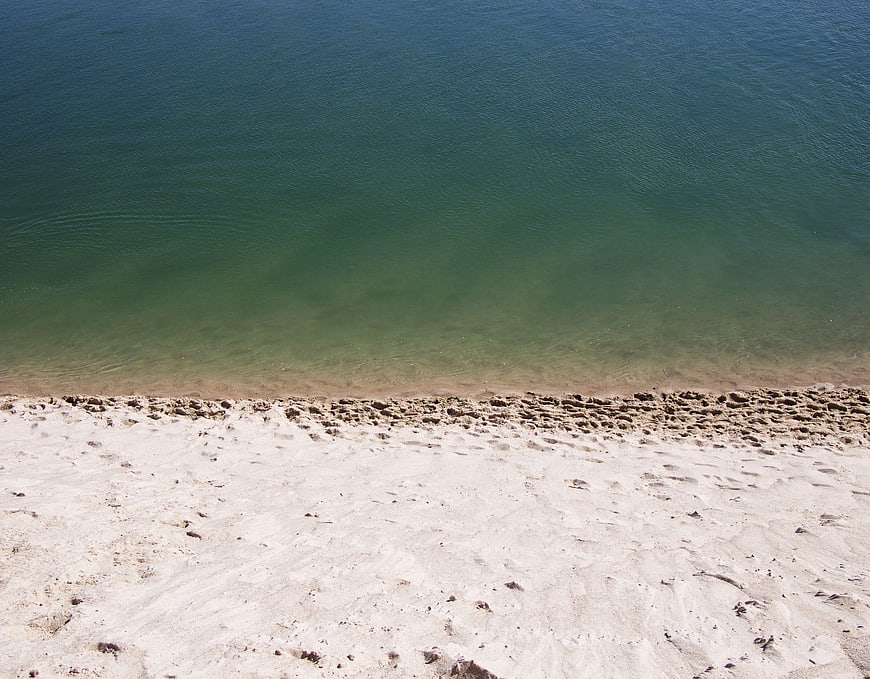 Aerial view of turquoise ocean water meeting sandy beach