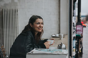 Smiling woman drinking coffee in a cafe window