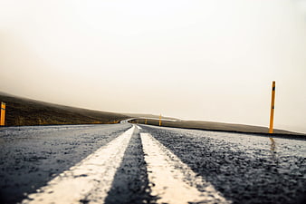 Low angle view of wet asphalt road with white lines