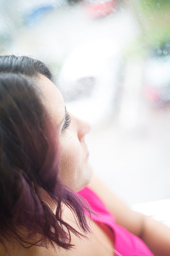 Close-up profile of woman looking out rainy window
