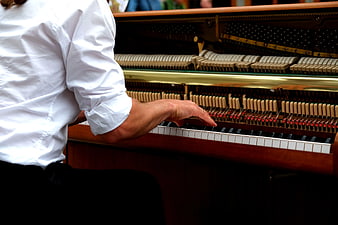Close-up of hands playing upright piano keys