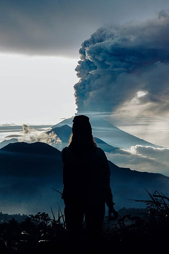 Silhouette of Hiker Watching Volcanic Eruption at Sunrise