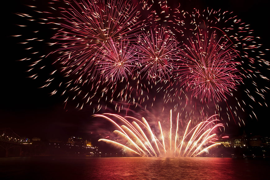 Vibrant red fireworks exploding over city skyline at night